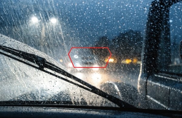 Heavy rain on a truck windshield with a failing wiper blade creating dangerous blind spots and streaks