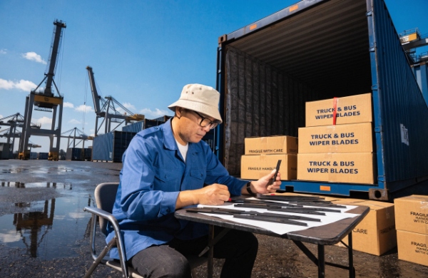 Shipping container full of truck and bus wiper blades being inspected upon arrival at port, quality check in progress