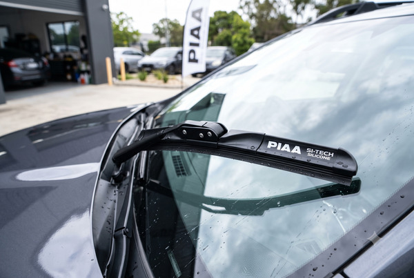 Realistic view of premium PIAA silicone wiper blades installed on a modern car windshield